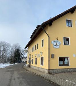 ein gelbes Gebäude an der Straßenseite in der Unterkunft Gasthof zum Kirchenwirt in Kirchdorf am Inn