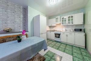 a kitchen with white cabinets and a green floor at Двухкомнатные апартаменты рядом с вокзалом in Sochi