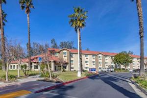 a building with palm trees in front of a street at Comfort Inn Fontana in Fontana