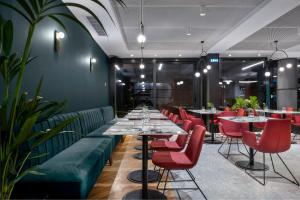 a restaurant with long tables and red chairs at Hotel Tim's in Skopje