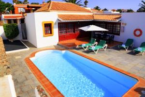 a swimming pool in front of a house at Vip Villas - Caleta Dorada in Caleta De Fuste