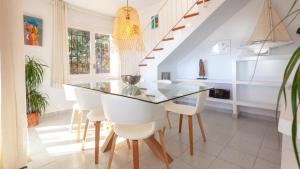 une salle à manger avec une table en verre et des chaises blanches dans l'établissement Villa Coral, à Tamariu