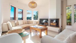 Elle comprend un salon doté d'un mobilier blanc et d'une cheminée. dans l'établissement Villa Coral, à Tamariu
