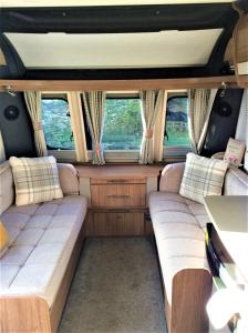una vista interior de una furgoneta con sofás y ventanas en Le Boterff Gites et Camping en Saint-Mayeux