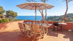 ein Tisch und Stühle mit einem Sonnenschirm auf einer Terrasse in der Unterkunft Villa Coral in Tamariu