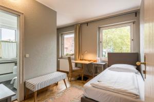 a bedroom with a bed and a desk and two windows at Hotel Hiltruper Hof in Münster