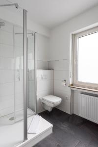 a white bathroom with a toilet and a shower at Hotel Hiltruper Hof in Münster