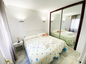 フエンヒロラにあるAurinko 1 Tranquilo y Agradable Apartamento en Los Bolichesのベッドルーム1室(ベッド2台、大きな鏡付)
