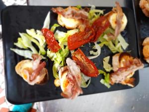 um prato preto de comida com bacon e salada em Auberge La Caverne em Laruns