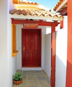 uma porta vermelha num edifício branco com um vaso de plantas em Vip Villas - Caleta Dorada em Caleta de Fuste