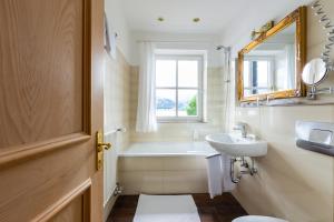 a bathroom with a sink and a tub and a mirror at Seehotel Schlierseer Hof in Schliersee