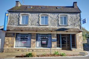 a stone building with windows and doors on a street at Ty Keramor in Hôpital-Camfrout