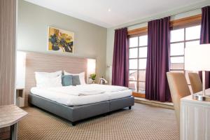 1 dormitorio con 1 cama grande y cortinas moradas en Hotel Raffel, en Jennersdorf