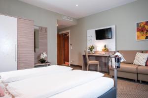 イェナースドルフにあるHotel Raffelのベッド2台とソファが備わるホテルルームです。