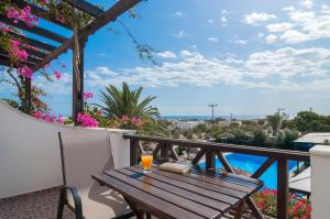 a wooden table on a balcony with a glass of orange juice at Holiday Beach Resort Santorini in Perivolos