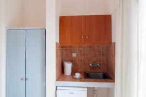 una pequeña cocina con armarios de madera y fregadero en Holiday Beach Resort Santorini, en Perivolos