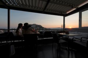two people sitting at a restaurant looking out at the sunset at Hotel Adonis in Athens