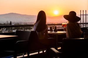 
two people sitting at a table with a view of the ocean at Hotel Adonis in Athens
