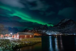 an island with a red house and the aurora in the sky at Arctic Resort Lofoten in Ramberg