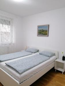 - une chambre blanche avec 2 lits et une fenêtre dans l'établissement Apartments Dora, à Zagreb