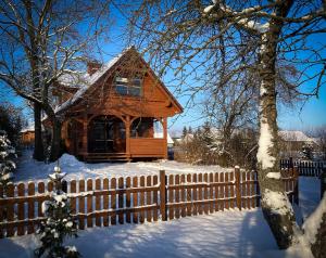 drewniany dom z płotem w śniegu w obiekcie Sosnowy domek w rezerwacie nad Narwią w mieście Bokiny