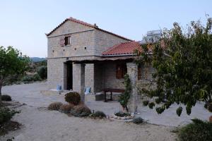 uma casa de pedra com um banco à frente em Oceanis cottage house em Órmos Koumaíïkon