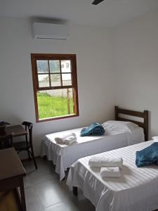 twee bedden in een kamer met een raam bij Pousada Cipó Paraty in Paraty