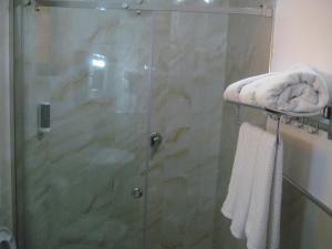 una doccia con porta in vetro con asciugamani su un appendiabiti di Drini Hotel a Durrës