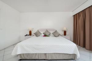 um quarto branco com uma grande cama branca com almofadas em Appartement 1 chambre Sapphire Beach em Cupecoy
