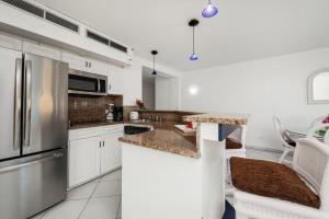 uma cozinha com armários brancos e um frigorífico de aço inoxidável em Appartement 1 chambre Sapphire Beach em Cupecoy