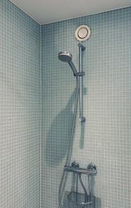 a shower in a bathroom with blue tiled walls at ApartmentInCopenhagen Apartment 93 in Copenhagen