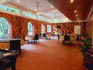 a dining room with wooden walls and tables and chairs at Orchid Trails Resort in Sultan Bathery