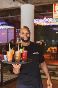a man is holding a tray of drinks at Hotel Bazar in Rotterdam