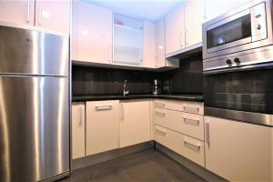 a kitchen with white cabinets and a stainless steel refrigerator at Estepona East Apartment MIA in Estepona