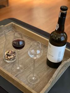 a bottle of wine and two glasses on a tray at Appartement de Gouw in Noordgouwe