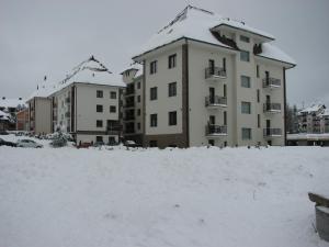 a building covered in snow in front of buildings at B&S Apartments in Zlatibor