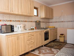 cocina con armarios de madera, fregadero y nevera en Casa Stefania 1, en Călimăneşti