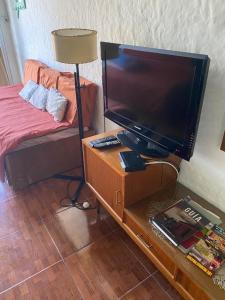 Habitación con TV, cama y mesa con lámpara. en Rincón de Araus, en Colonia del Sacramento