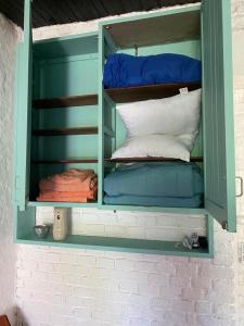 un armario verde lleno de almohadas y mantas en Rincón de Araus, en Colonia del Sacramento
