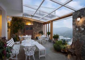 ein Restaurant mit weißen Tischen und Stühlen und einem großen Fenster in der Unterkunft Hills & Hues in Thekkady