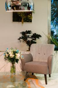 a chair and a vase with flowers on a glass table at Hôtel Hélios in Juan-les-Pins
