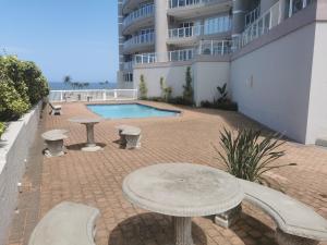 a patio with a table and benches next to a building at Seahorse unit 4 in Scottburgh