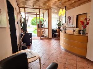 a lobby with a counter and chairs and a reception desk at Hotel am Hachinger Bach by Blattl in Neubiberg