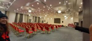 a large room with red chairs and a podium at Golden Tulip Royaume in Alger