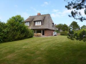 a house with a gray roof on a grass field at Strandhaus Helene in Wenningstedt