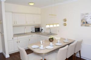 a kitchen with a wooden table and white cabinets at C-Haus Cordula, App 41 in Wenningstedt
