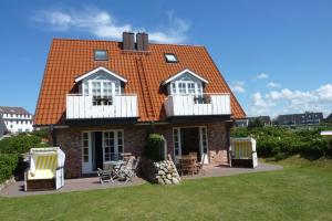 una casa con techo naranja y balcones blancos en LH Isernhagenhof, App 1, en Wenningstedt
