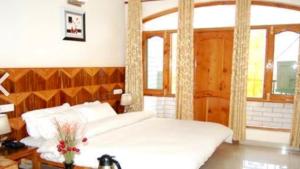 a bedroom with a white bed with a wooden headboard at Hotel Sanjeevny in Bajaura +39 photos