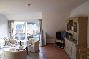 a living room with a couch and a tv at C-Haus Constanze, App 46 in Wenningstedt