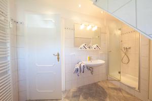 a white bathroom with a sink and a shower at C-Haus Constanze, App 46 in Wenningstedt +7 photos